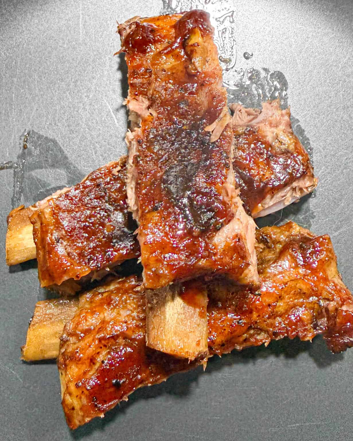 A pile of oven-roasted baby back ribs on a black plate