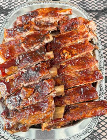 A big plate of oven baked barbecue brushed ribs so tender they fall of the bone