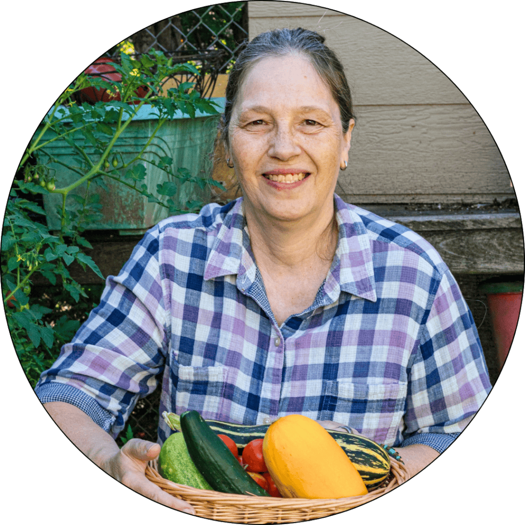 Debbie in her garden with veggies in her hands