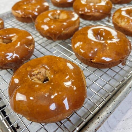 Apple cider donuts on a cooling rack dipped in maple glaze