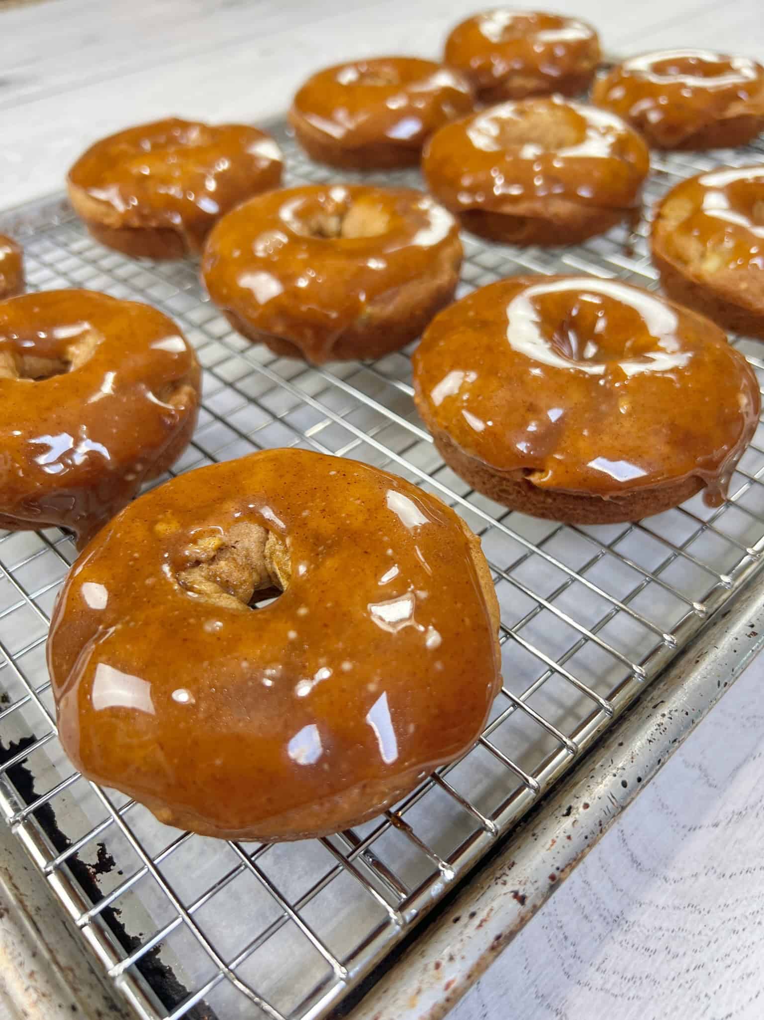 Apple cider donuts on a cooling rack dipped in maple glaze