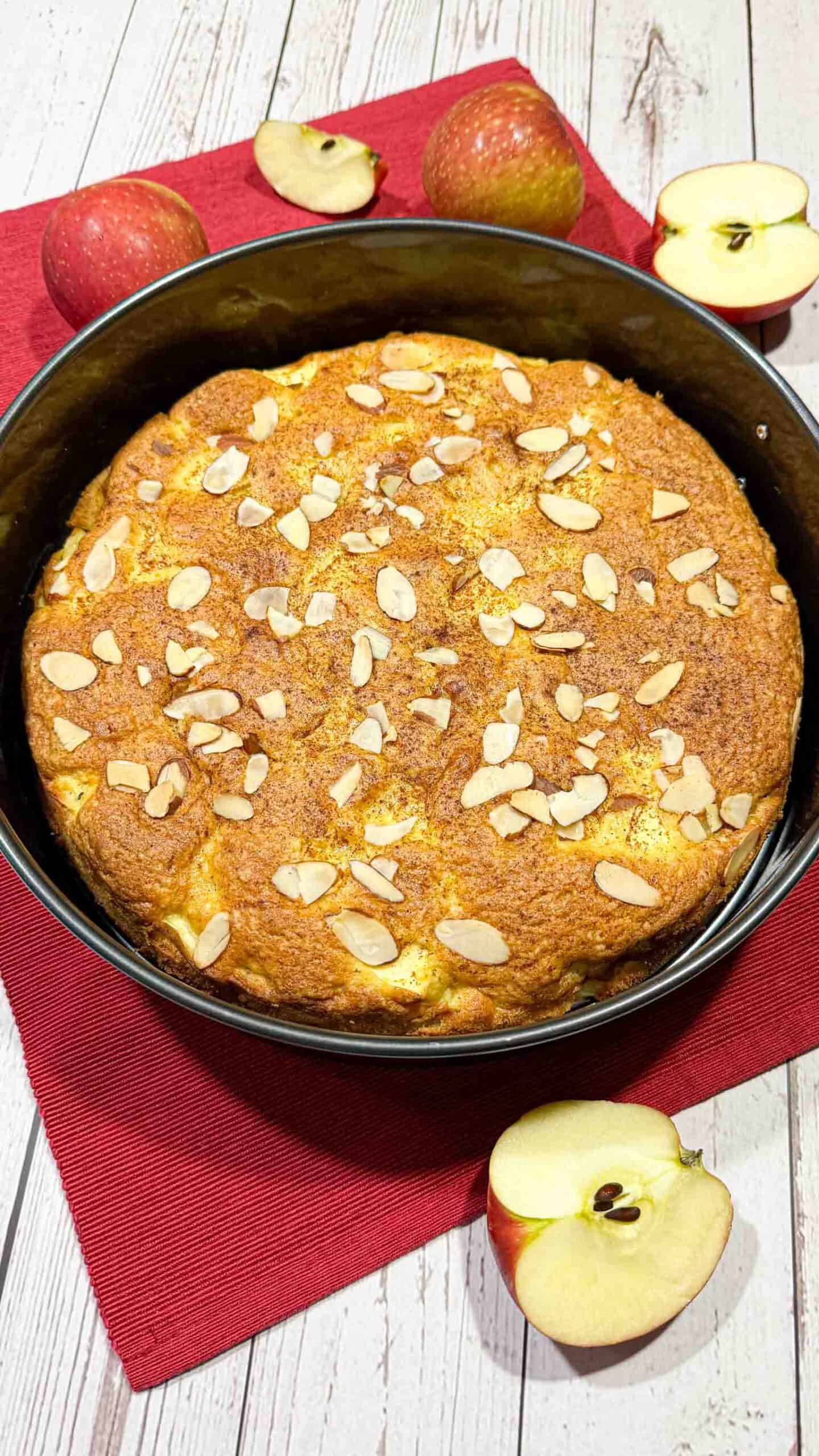 Whole apple cake topped with sliced almonds in springform