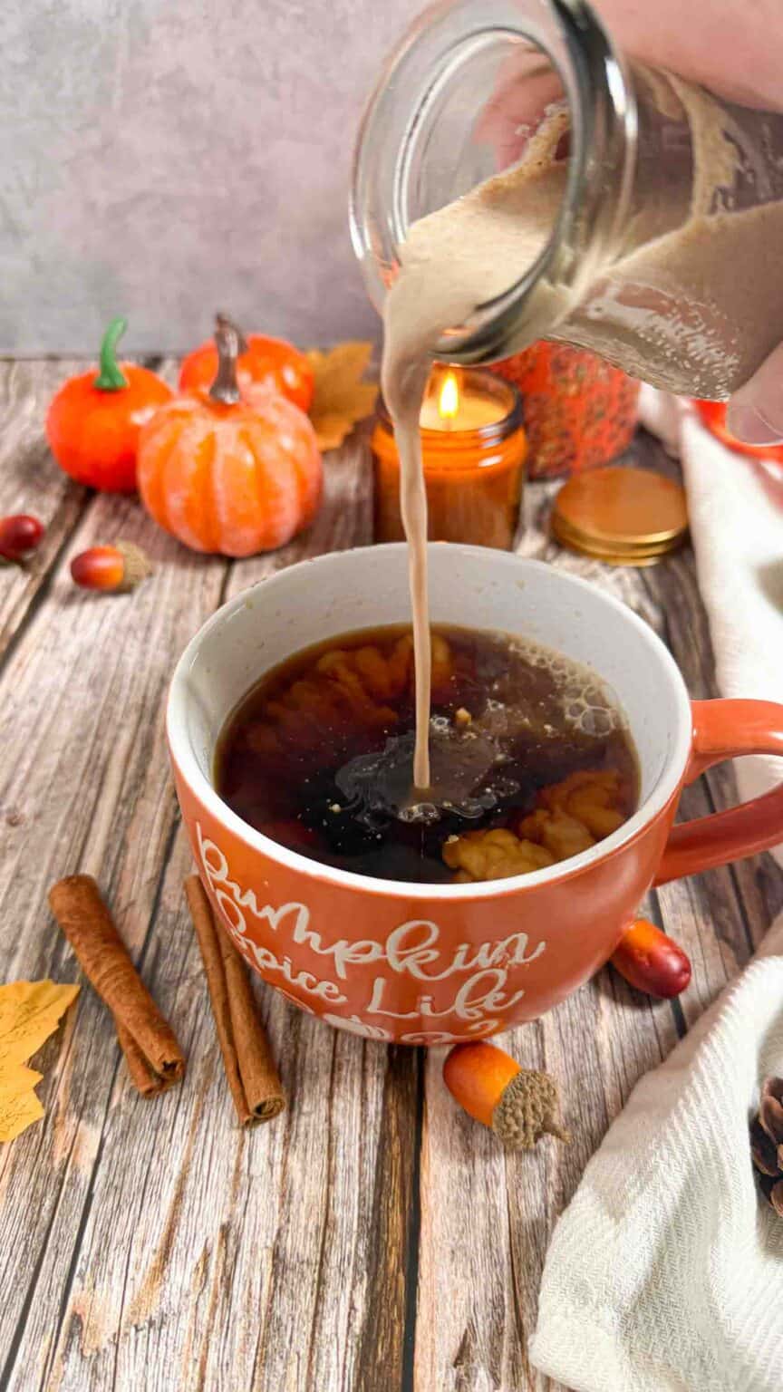 pouring in pumpkin spice coffee creamer in hot coffee